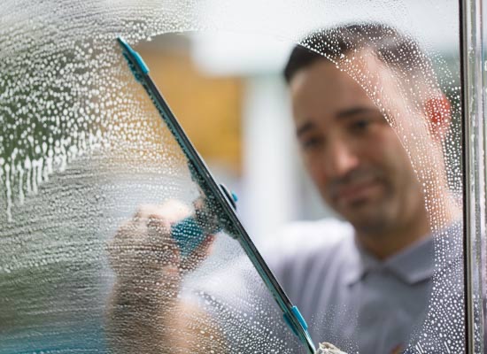 A Chief window cleaner squeegeeing a soapy window